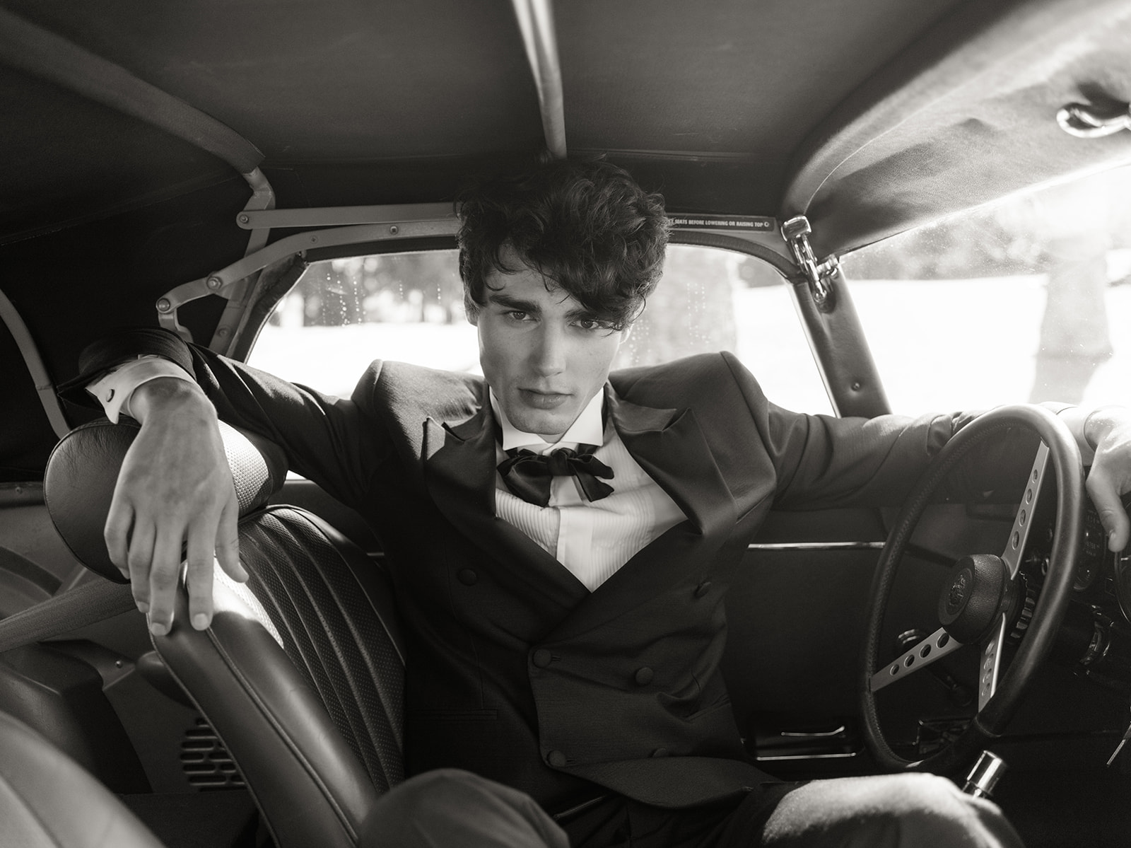 Black-and-white groom portrait inside a classic Jaguar on the French Riviera